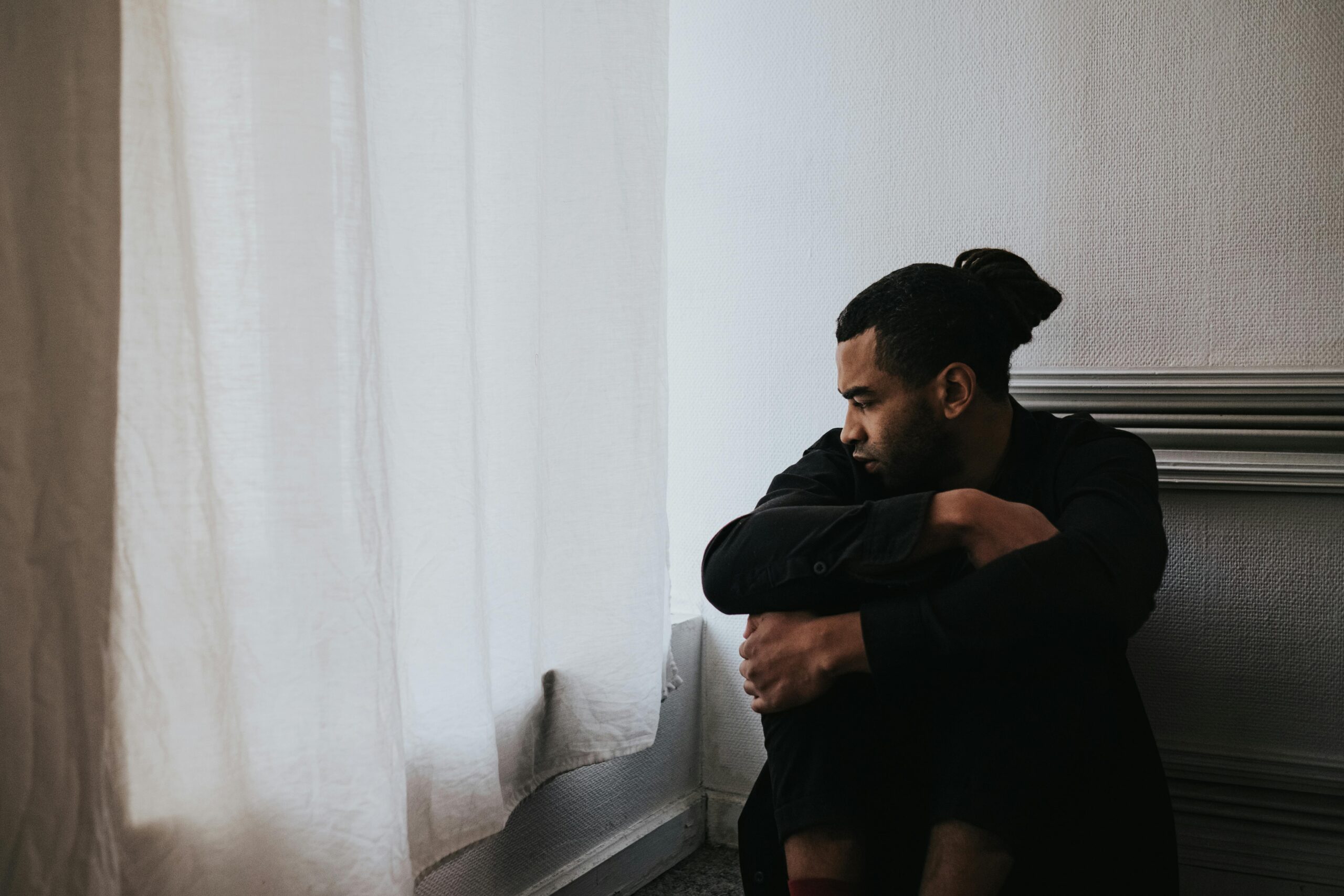 A person sitting on the ground, looking sad.